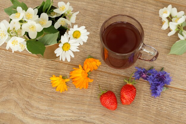 Tasse de thé en verre avec fraises et fleurs