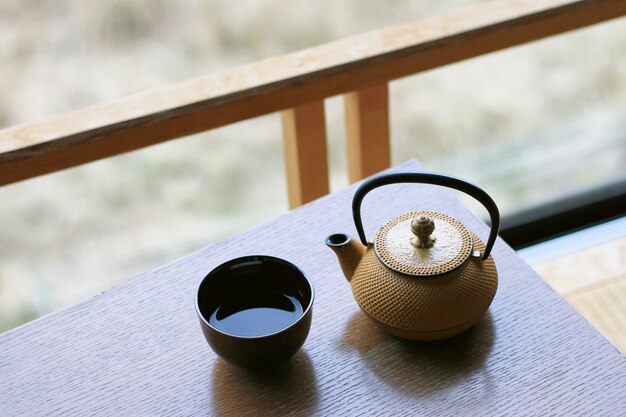 Tasse de thé vert chaud et théière sur une table