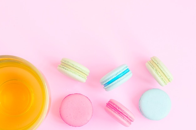 Tasse de thé vert et macarons colorés sur fond rose