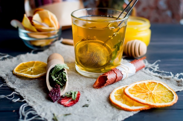 Tasse de thé vert à la menthe, tranche de citron, rouleau de fruits secs et feuilles de thé à la menthe