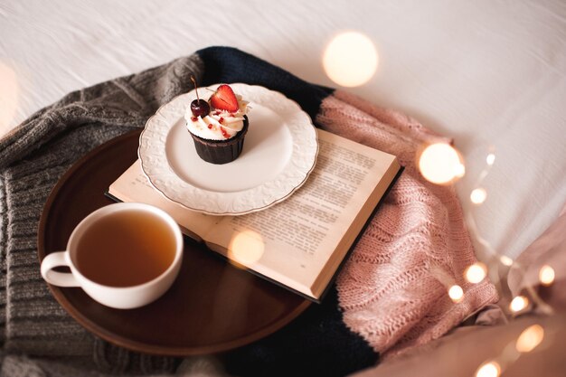 Tasse de thé vert avec petit gâteau savoureux et livre ouvert