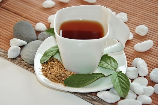 Tasse de thé vert avec des pierres blanches et un sol en bambou