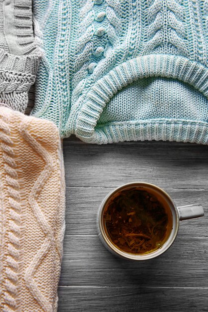 Photo une tasse de thé et des vêtements chauds sur un fond en bois