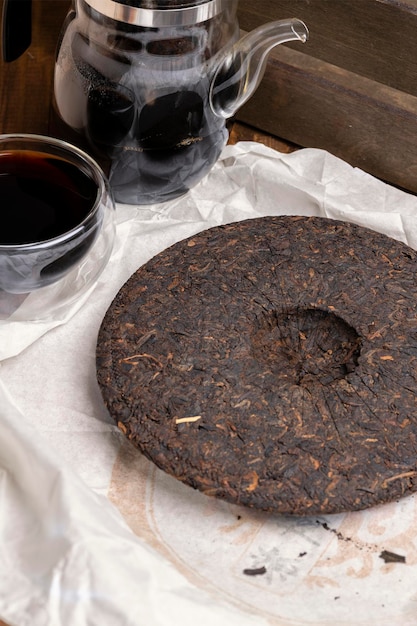 Tasse et théière en verre avec thé puerh noir chinois Thé puer mûr sous forme de galette ronde