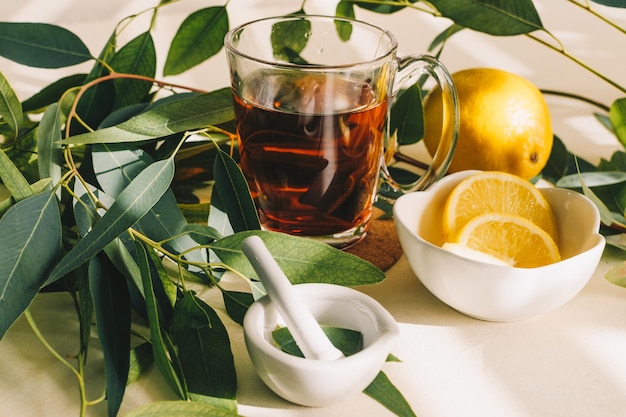 Tasse de tisane citron et feuilles d'eucalyptus dans un petit mortier en céramique blanche