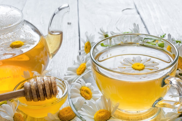 Tasse de tisane avec fleurs de camomille et miel et théière