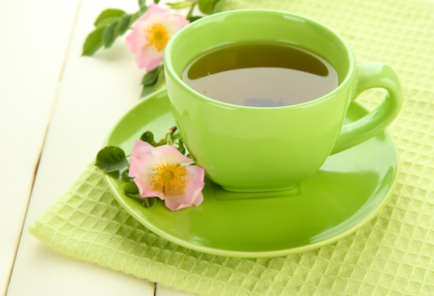 Tasse de tisane avec des fleurs de rose de la hanche sur une table en bois blanc