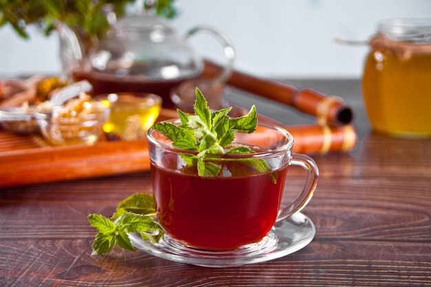 Tasse de tisane à la menthe avec des herbes sèches sur le plateau