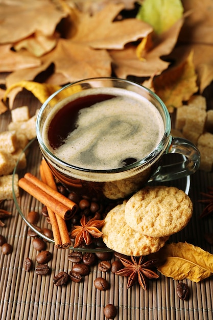 Tasse en verre de biscuits savoureux de café et de feuilles d'automne sur le fond en bois