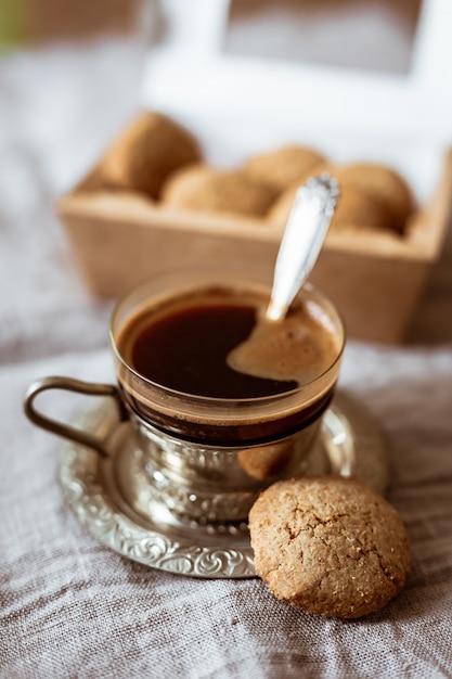 Une tasse en verre de café noir dans un porte-verre sur une soucoupe en métal