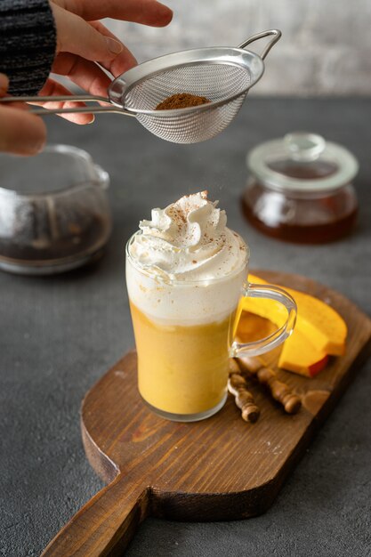 Une tasse de verre de cappuccino épicé à la citrouille sur fond gris