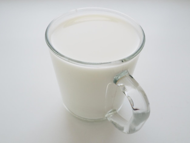 Tasse en verre avec du lait sur fond blanc. Aliment protéiné diététique