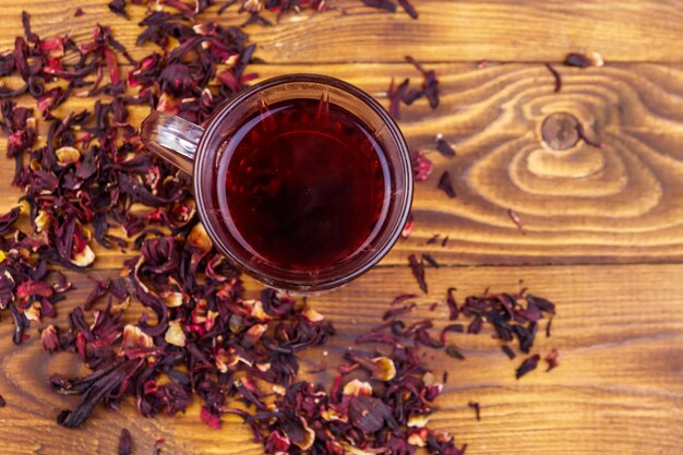 Tasse en verre de roselle de carcade de thé d'hibiscus rouge sur une table en bois
