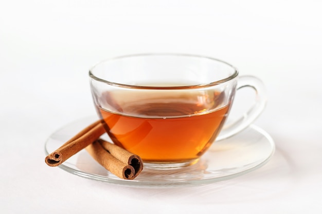 Tasse en verre de thé avec des bâtons de cannelle.