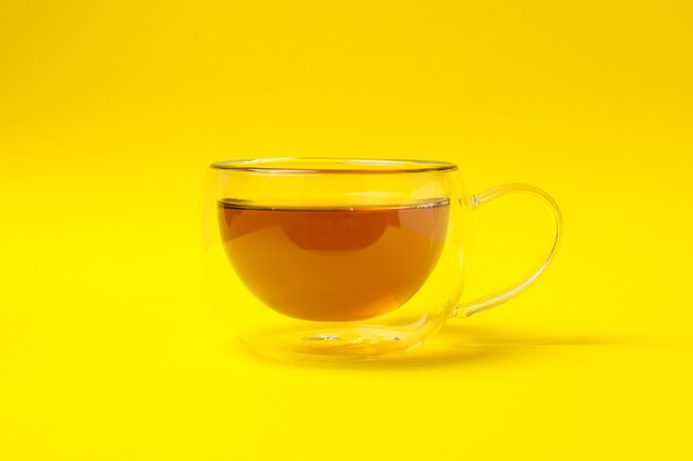 Tasse en verre de thé à la camomille sur jaune