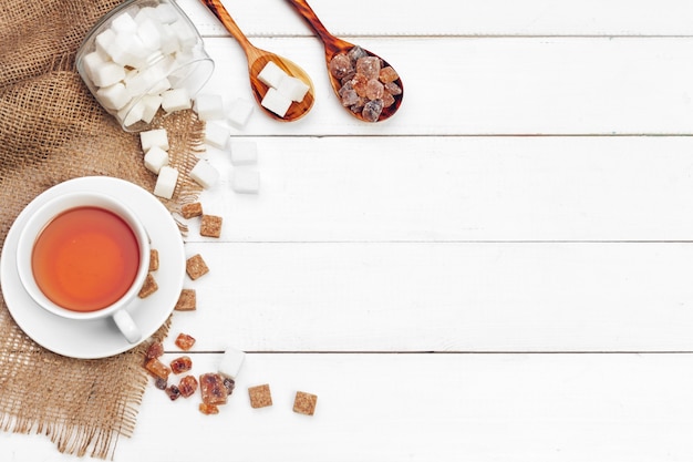 Tasse en verre de thé chaud avec du sucre sur la table