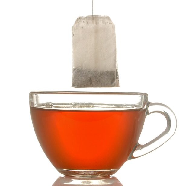 Tasse en verre avec thé et sachet de thé gros plan sur fond isolé blanc