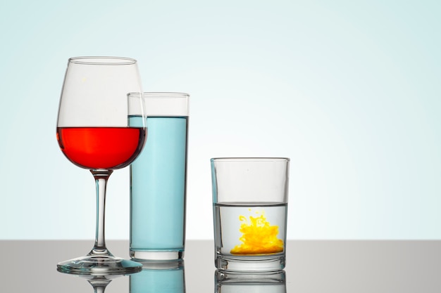 Tasse et verres en verre avec un fond blanc et boissons de différents types et couleurs