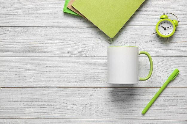 Tasse vide et fournitures de bureau sur fond de bois blanc