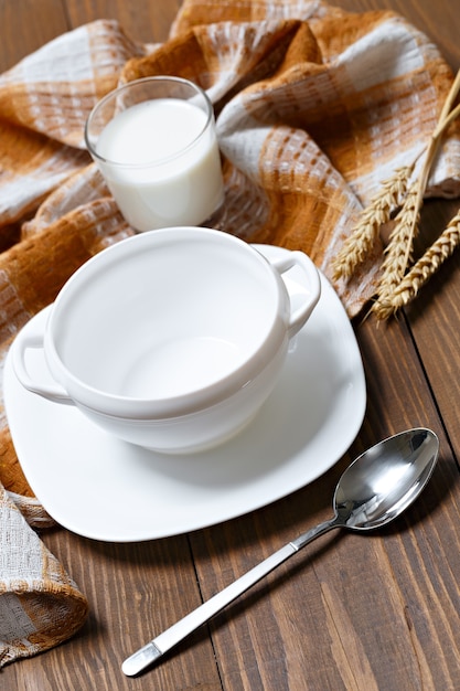 Tasse vide de soupe et un verre de lait sur une table en bois.