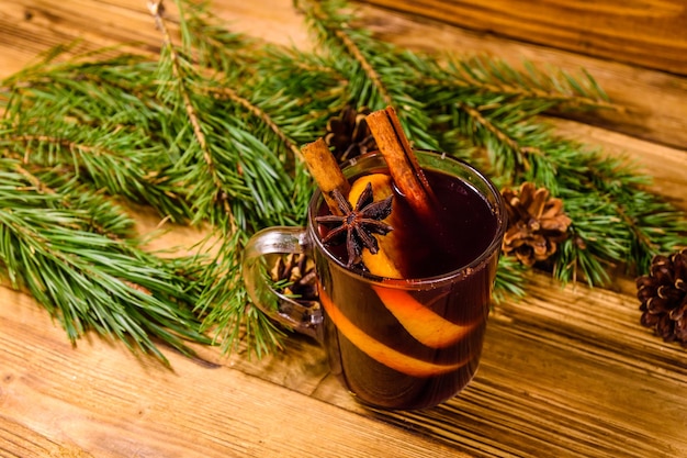 Tasse de vin chaud avec des branches de cannelle et de sapin sur une table en bois rustique