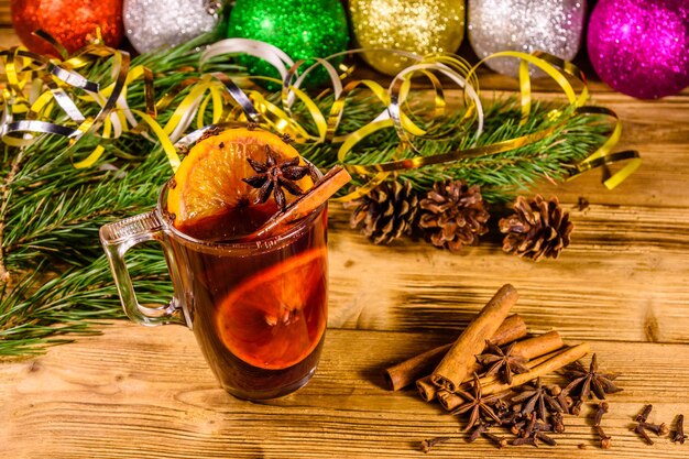 Tasse de vin chaud à la cannelle, décorations de Noël et branches de sapin sur table en bois rustique