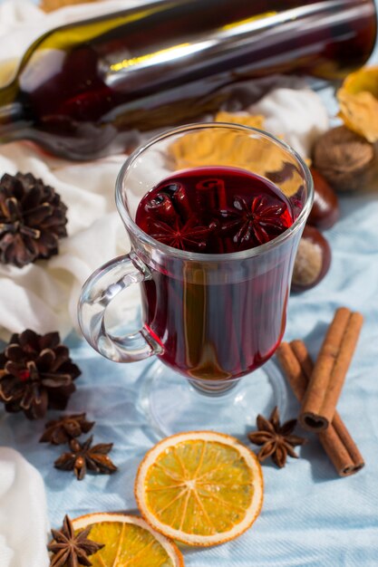 Une tasse de vin chaud avec des épices, une bouteille, des feuilles sèches et des oranges sur la table. Humeur d'automne, méthode pour rester au chaud dans le froid, fond, lumière du matin.