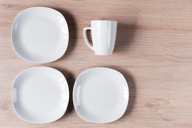 Tasses et assiettes en céramique blanche sur l'image de fond en bois