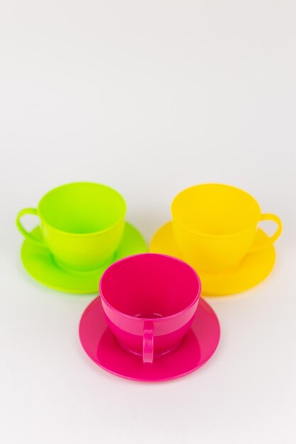 Tasses et assiettes en plastique multicolores sur un ensemble de cuisine de fond blanc