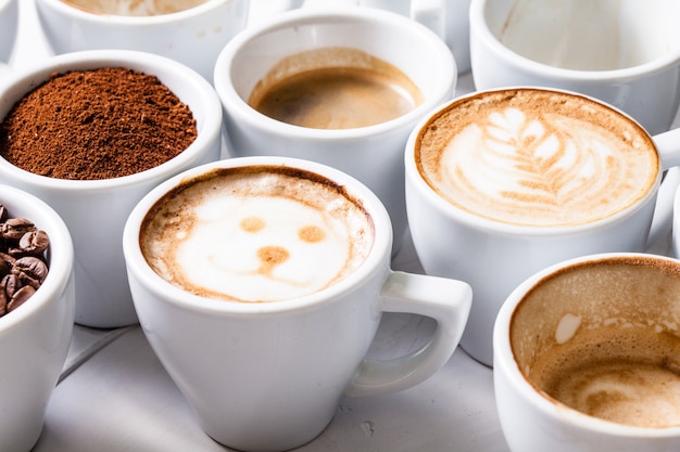 Tasses blanches de différentes étapes de préparation du cappuccino. Concept d'amateur de café nature morte