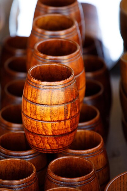 Des tasses en bois marron en forme de tonneau se tiennent en rangées sur une étagère en bois.