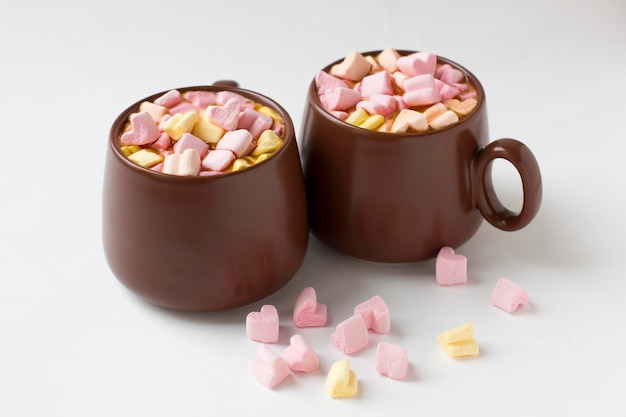 Tasses brunes de chocolat chaud avec des guimauves en forme de coeur sur fond blanc Fond romantique avec chocolat chaud Concept d'amour pour la Saint-Valentin ou le mariage