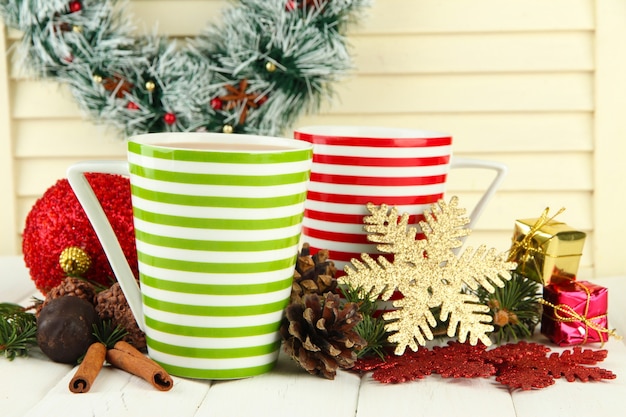 Tasses de cacao chaud avec des chocolats et des décorations de Noël sur table sur fond de bois