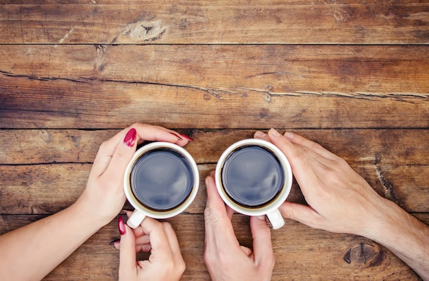 Tasses avec un café dans les mains des hommes et des femmes. Mise au point sélective.