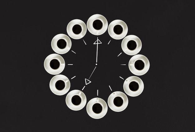 Les tasses à café empilées dans une horloge circulaire se composent de vingt tasses de temps de concept de fond noir à c...