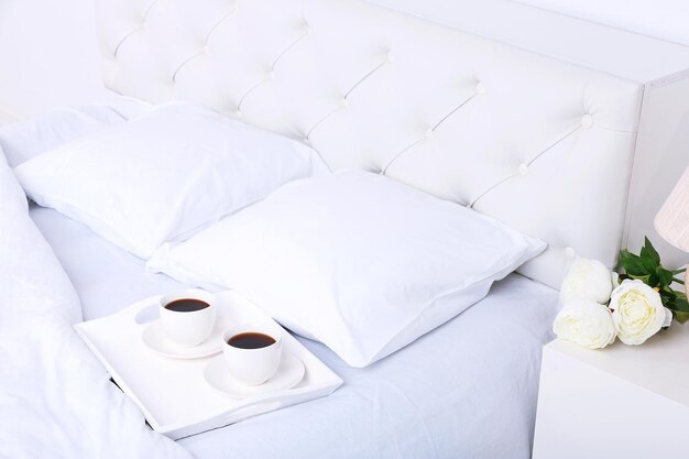 Tasses de café sur un lit moelleux confortable avec oreillers