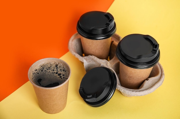 Tasses à café en papier à emporter avec couvercles en plastique et support en carton sur fond de couleur