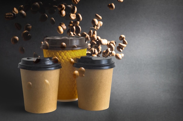 Tasses à café en papier avec grains de café sur fond sombre. Modèle et concept de fond créatif pour les cafés.