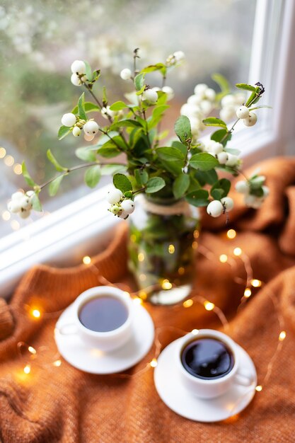 Tasses de café près de la fenêtre avec bouquet