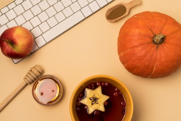 Tasses jaunes de thé aux baies chaudes avec des pommes clavier blanc miel citrouille automne maison confort de l'espace de travail