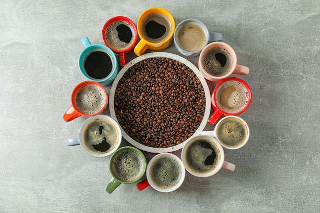 Tasses multicolores de café et grains de café sur fond gris