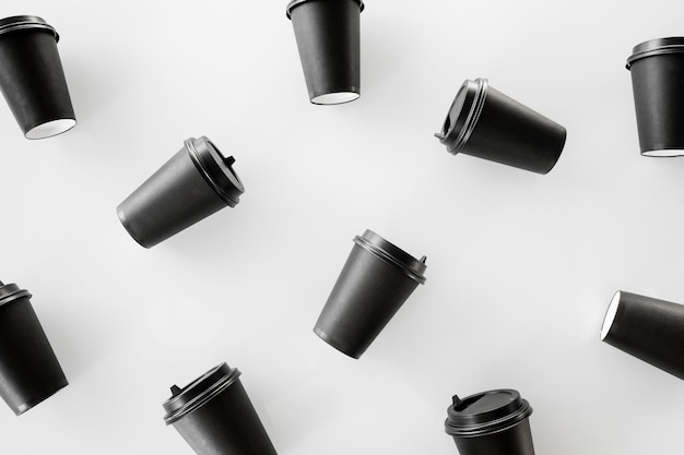 Des tasses de papier noires éparpillées sur un fond blanc recyclent des tasses en papier artisanal