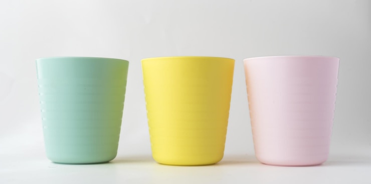Des tasses en plastique isolées sur fond blanc, des tasses de plastique colorées pour enfants