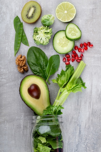 Tasses de pot en verre avec des feuilles de laitue légumes verts santé, citron vert, pomme, kiwi, avocat