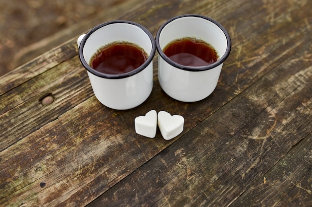 Tasses de thé émaillées dans la nature sur une surface en bois avec guimauve