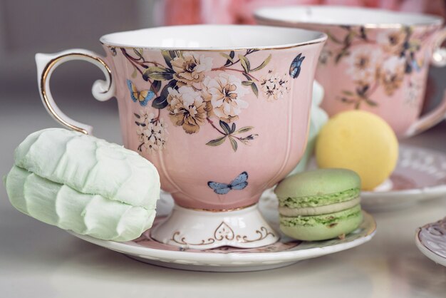 Tasses à thé rose avec ornement floral et bonbons macaron