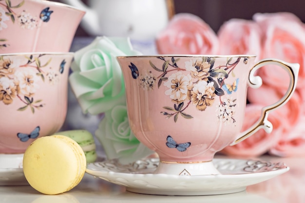 Tasses à thé rose avec ornement floral et bonbons macaron