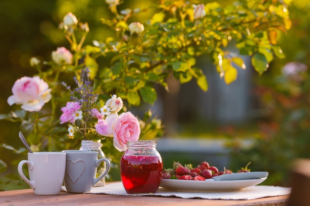 Tasses à thé avec des roses roses sur une table en bois le matin