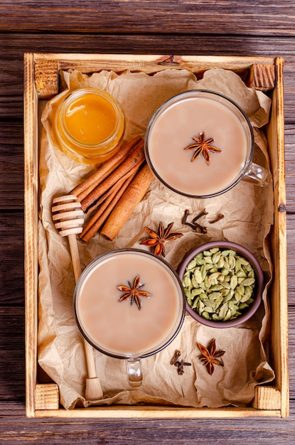 Tasses en verre de thé indien traditionnel Masala thé sur un plateau avec des ingrédients