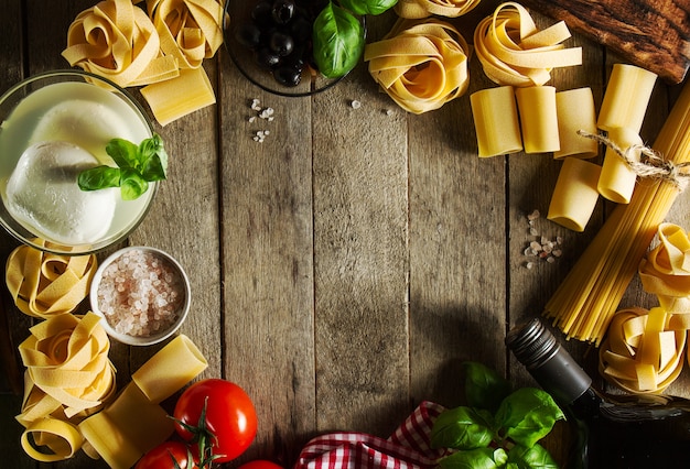 Photo tasty colorful fresh italian food concept avec divers pâtes spaghetti, mozzarella au fromage, basilic frais, tomates, huile d'olive, épices. concept de cuisine. lieu pour le texte.